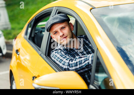 Photo de l'homme en chemise à carreaux du pilote assis dans le taxi jaune jour d'été Banque D'Images