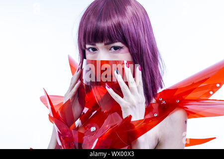 Femme Asiatique Bande dessinée cosplayeuse avec costume futuriste en rouge, faite de pvc et plastiques transparents. orientale Banque D'Images