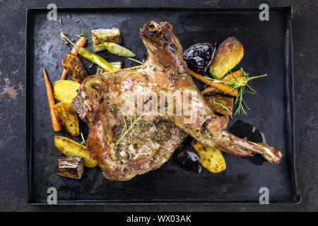 Un barbecue et de l'épaule d'agneau avec des pommes de terre et légumes en vue d'en haut sur une vieille feuille de métal Banque D'Images