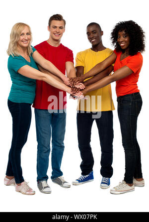 Groupe de jeunes amis multiculturelle posant avec mains sur les mains en vous regardant Banque D'Images