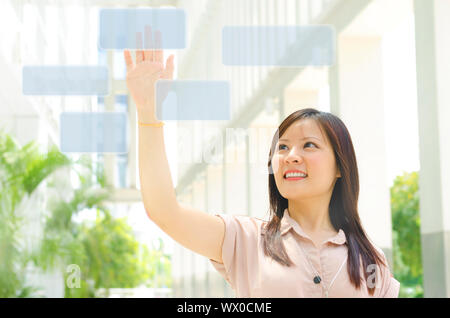 Young Asian woman doigt appuyant sur le moniteur à écran tactile Banque D'Images