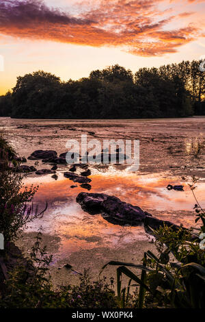 Le lever du soleil sur un petit lac appelé Liden Lagoon à Swindon, Wiltshire. Banque D'Images