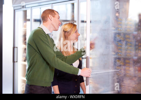 Un couple heureux l'épicerie dans la section des surgelés d'un supermarché Banque D'Images