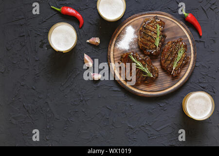Installations pour Barbecue, des steaks, de la bière, pierre noire, tomates cerises, les poivrons, le romarin. Manger à l'extérieur. copy space Banque D'Images