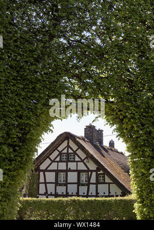 Maison à pans de bois d'un mètre de haut derrière haie avec voûte, Monschau, Eifel, Allemagne, Europe Banque D'Images