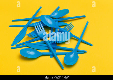 Groupe d'jetables en plastique bleu couteaux, fourchettes et cuillères sur un fond jaune. Banque D'Images