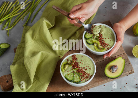 Smoothie vert bol avec l'avocat, kiwi frais et vert concombre à la main sur un fond de pierre Banque D'Images