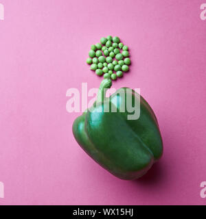 Poivron vert et une pincée de pois verts sur fond rose Banque D'Images