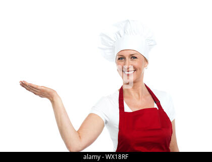 Female chef en uniforme adéquat présentant copie espace against white background Banque D'Images