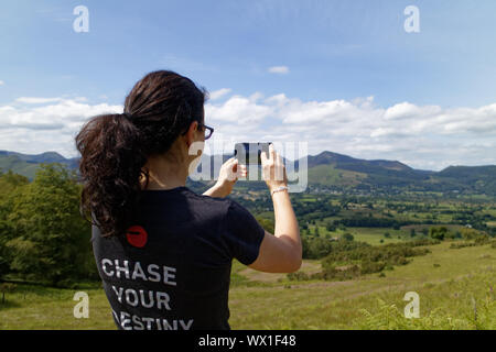 Une femme prise de photos dans le Lake District en utilisant son téléphone portable Banque D'Images