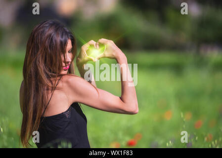 Belle femme souriante. Symbole coeur vert en forme avec l'intérieur de la torche. L'amour, la nature concept. L'écologie et la durabilité. Banque D'Images