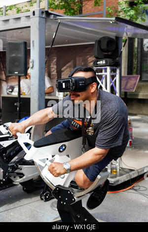 Un homme portant des lunettes de réalité virtuelle et de l'équitation un simulateur moto Banque D'Images