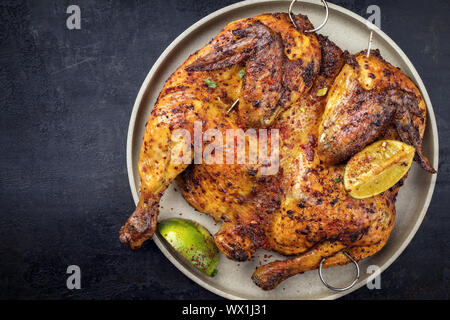 Spatchcocked traditionnelle du poulet barbecue al mattone avec les tranches de citron en vue d'en haut sur une plaque avec copie espace à gauche Banque D'Images