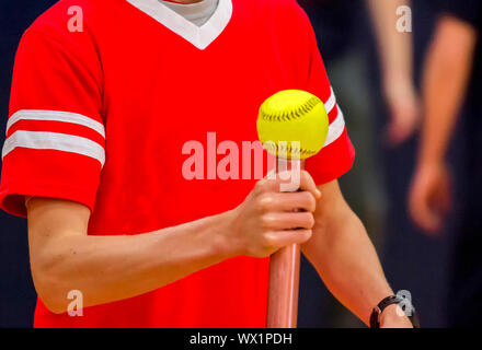 Une école est une athlète d'équilibrage softball sur un baton pour une course de relais. Banque D'Images