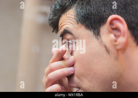 Jeune homme de mettre dans son oeil de verre de contact Banque D'Images