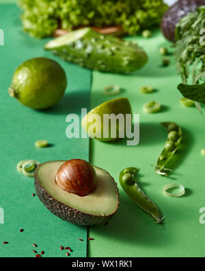 Gren légumes pour salade - laitue, pois verts, bois, avocat, la chaux sur un fond vert deux tons. Banque D'Images