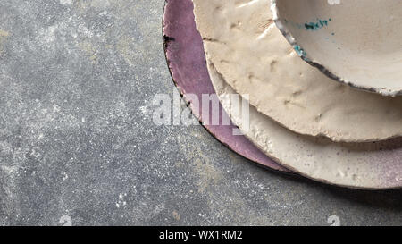 Peint Vintage assiettes, bols émaillés à la main sur table béton gris avec de l'espace libre texte ror. Banque D'Images