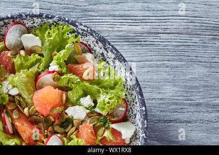 Un quart de l'assiette de salade végétarienne avec des ingrédients biologiques naturelles-légumes, fruits, fromage, graines sur un onglet en bois gris Banque D'Images