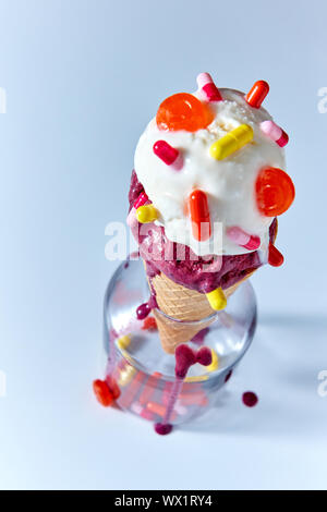 Boules de glace appétissante dans un cornet gaufré avec verre capsules comprimés dans une bouteille sur un fond bleu. Vue d'en haut Banque D'Images