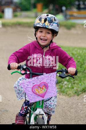 Une petite fille (5 ans) rayonnant de joie comme les manèges son vélo Banque D'Images