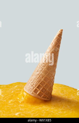 Fallen cornet gaufré avec glace jaune sur fond gris avec copie espace. Banque D'Images