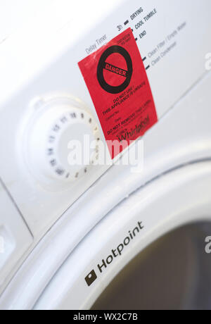 Signe de danger rouge collé sur la face avant d'un sèche-linge Whirlpool Hotpoint blanc Banque D'Images