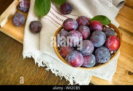 Les prunes mûres dans un grand panier en osier. Banque D'Images