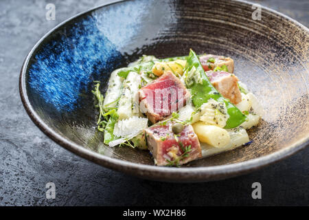 Tataki de thon poêlé moderne salade de filet avec du sucre d'asperges blanches s'enclenche et parmesan en vue de dessus sur une plaque Banque D'Images