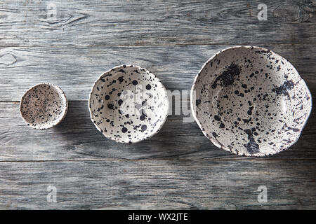 Bols en céramique de différentes tailles sont vides sur un fond de bois gris. Mise à plat de vaisselle en porcelaine faites à la main. Banque D'Images