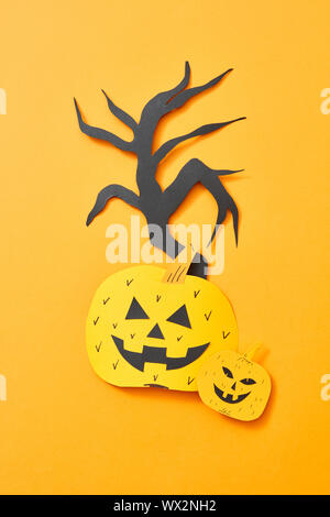 Citrouilles effrayantes et un arbre de tricot document présenté sur un fond orange avec copie espace. Mise en page de l'Halloween. Mise à plat Banque D'Images