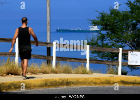 Bahia de Pozuelos, Carabobo, Venezuela. 16 Sep, 2019. Le 16 septembre 2019. Un résident exerce sur la colline El Morro pendant qu'en arrière-plan d'un navire reste dans la baie de Guaraguao Pozuelos, près du dock, dans la ville de Puerto la Cruz. La grande incertitude est de savoir s'il y aura des négociations d'achat et de vente pour les sanctions imposées par le gouvernement des États-Unis sur le Venezuela. À Puerto la Cruz, Venezuela. Photo : Juan Carlos Hernande. Photo : Juan Carlos Hernandez/ZUMA/Alamy Fil Live News Banque D'Images