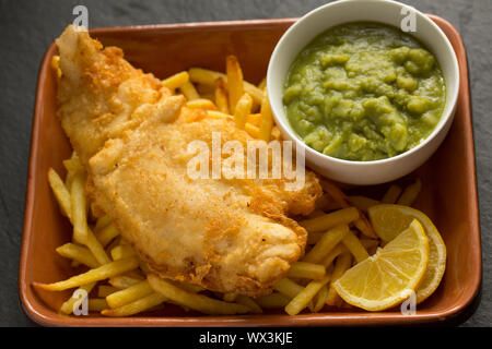 Un petit-déjeuner maison filet de lieu jaune de ligne-pris, Pollachius pollachius, qui a été trempée dans la pâte avant de la friture et servir avec des croustilles et four Banque D'Images