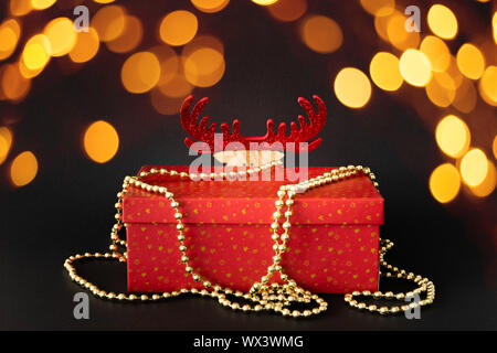 Boîte cadeau de décoration de Noël avec rennes cachés figure sur fond noir avec lumières bokeh Banque D'Images