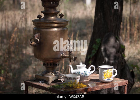 Samovar en bronze Vintage wood burning, tasses et théière sur table rouillée, en plein air préparer l'eau pour le thé brasserie, selective focus Banque D'Images