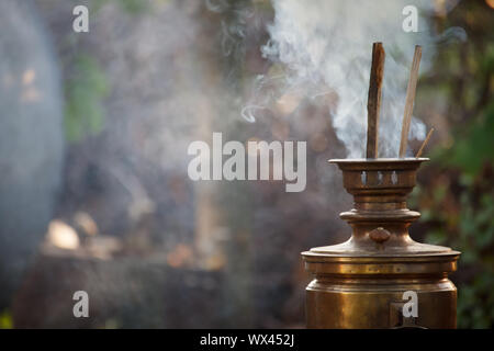 Embrasement de bronze ancien samovar, fixant le bois pour chauffer l'eau pour préparer le thé, selective focus Banque D'Images