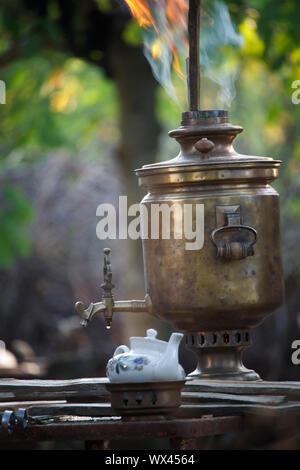 Embrasement de bronze ancien samovar, fixant le bois pour chauffer l'eau pour préparer le thé, selective focus Banque D'Images