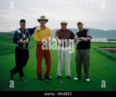 Portrait of smiling quatre hommes debout avec des clubs de golf sur un green de golf. Banque D'Images