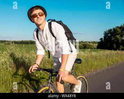 Jeune mec en blanc aime faire du vélo dans la campagne Banque D'Images