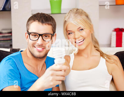 Image lumineuse de l'heureux couple holding energy saving bulb (accent sur la femme) Banque D'Images