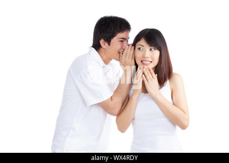 Portrait de jeune homme whispering a secret de femme isolé sur fond blanc. Banque D'Images