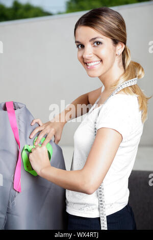 Portrait of pretty female fashion designer travaille sur un mannequin avec tissu gris Banque D'Images