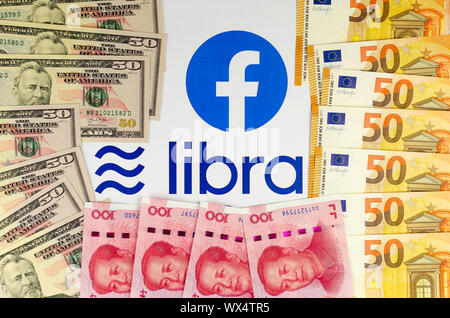 Facebook et sa monnaie Balance logos sur la brochure entouré d'US Dollars, Euros et le yuan chinois. Banque D'Images