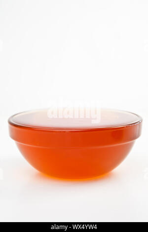 Bol plein de miel sur un fond blanc. Banque D'Images