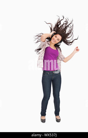 Brunette à écouter de la musique avec ses cheveux dans les cheveux contre fond blanc Banque D'Images