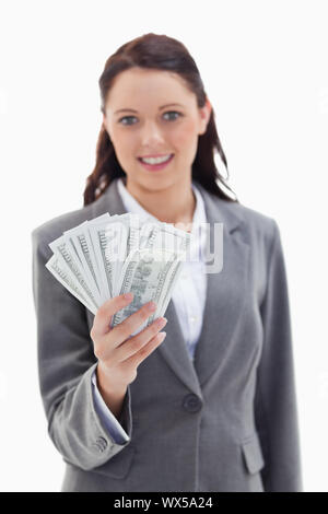 Close-up of a businesswoman smiling and holding a beaucoup de dollar bank note avec l'accent sur les billets de banque contre fond blanc Banque D'Images