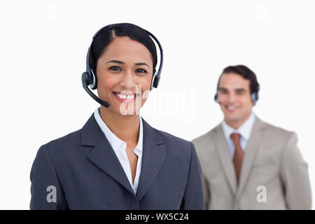 Assistance téléphonique avec l'employé souriant derrière son collègue sur un fond blanc. Banque D'Images