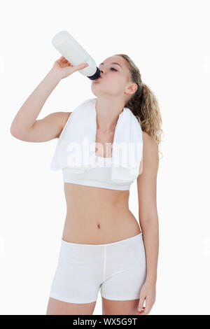 Jeune femme à boire de l'eau pendant les sports contre un fond blanc Banque D'Images