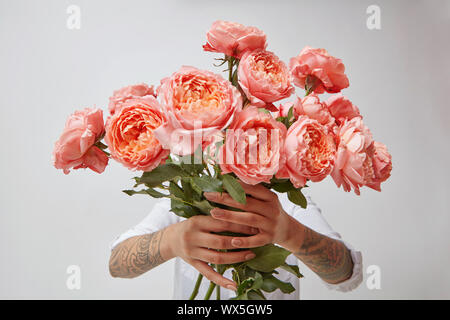 Young Girl's hands holding est un bouquet de fleurs fraîches dans ses mains avec tatoo dans une couleur de l'année 2019 de coraux vivants Panton Banque D'Images