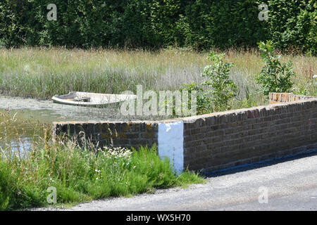 Une petite barque dans un frein de canne derrière un mur de pierre Sur l'île de Texel (pays-Bas) Banque D'Images