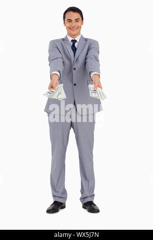 Portrait d'un homme donnant à beaucoup de dollars contre fond blanc
